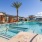 a pool surrounded by cabanas and palm trees
