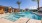 a pool surrounded by cabanas and palm trees